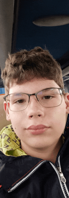 a young boy wearing glasses and a jacket with a zipper