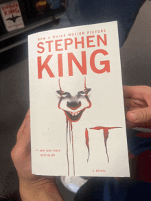 a person is holding a book by stephen king called it