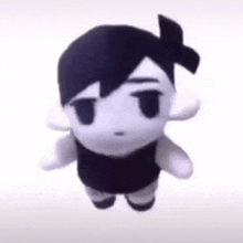 a black and white stuffed animal with a bow on its head is standing on a white surface .