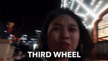 a woman says third wheel in front of a building