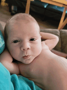 a newborn baby is laying on a blue blanket and making a funny face