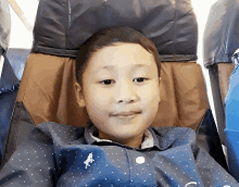 a young boy sits in a chair with his head resting on the back of the chair