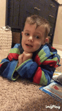 a young boy is laying on a carpet with a book on the floor that says " can you play " on it