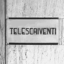 a sign on a wall says telescritti in black letters