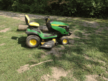 a green and yellow john deere lawn mower is parked on the grass