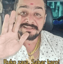 a man with a beard and mustache is sitting in a car and waving his hand .