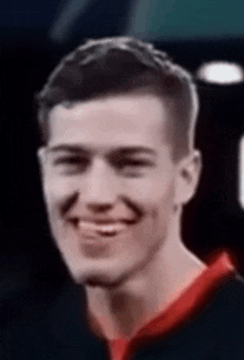 a close up of a man 's face with a red shirt on smiling .