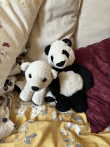 two stuffed animals are laying on a bed with pillows