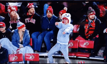 a group of people sitting in a stadium wearing utah hats and scarves