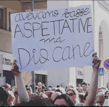 a person holding a sign that says avevamo basse aspettative ma dis cane