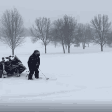 a snowmobile is parked in the snow and a person is playing golf