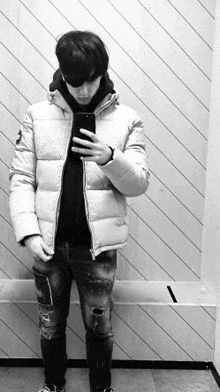 a man in a white jacket is taking a selfie in a black and white photo .