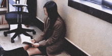 a girl is sitting on the floor reading a book