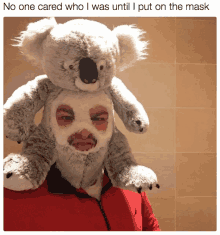 a man with a mask on his face holds a stuffed koala bear