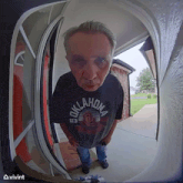 a man in an oklahoma shirt is standing in front of a door