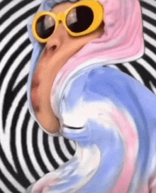 a person wearing sunglasses and a tie dye hoodie is standing in front of a hypnotic background .