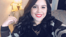 a woman wearing red lipstick and a gold necklace smiles for a picture