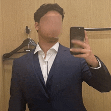 a man in a suit is taking a selfie with his face obscured .