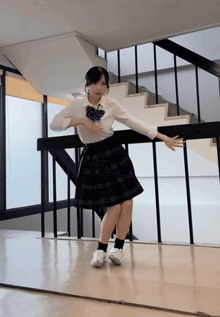 a girl in a school uniform is dancing in front of a mirror