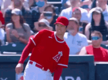 a baseball player wearing a red uniform with the letter a on it is throwing a ball in front of a crowd .