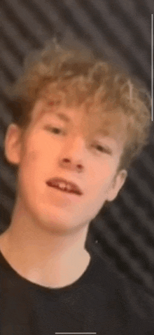 a close up of a young man 's face with a black shirt on .