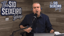 a man speaking into a microphone in front of a sign for the sid seixeiro show