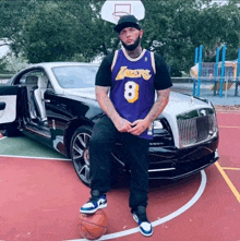 a man wearing a lakers jersey stands next to a basketball