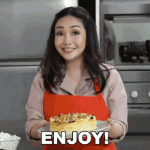 a woman in a red apron is holding a plate with a cake on it and the words enjoy written on the bottom