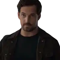 a man with a beard wearing a black shirt and brown jacket