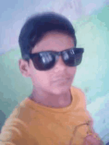 a young boy is wearing sunglasses and a yellow shirt .