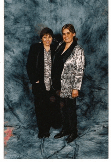 two women standing next to each other in front of a blue backdrop