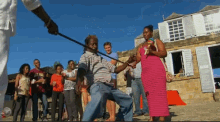 a group of people are standing in front of a building and one of them is wearing a red dress