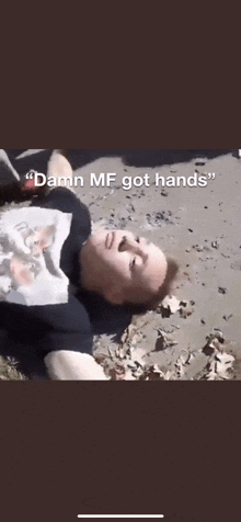 a man is laying on the ground with a t-shirt that says `` damn mf got hands '' .