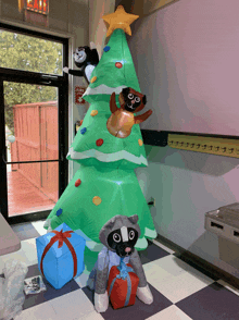 a large inflatable christmas tree with a raccoon sitting underneath it