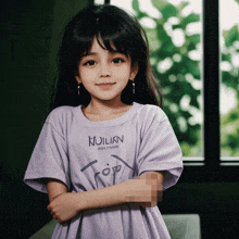 a young girl wearing a purple t-shirt that says ' noilkn ' on it