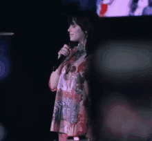 a woman is standing in front of a microphone on a stage .