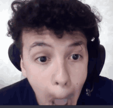 a young man with curly hair is wearing headphones and making a funny face