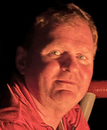 a close up of a man 's face with a red shirt