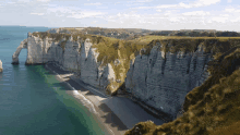 a cliff overlooking a body of water with a beach below