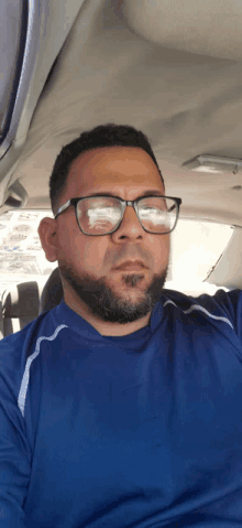 a man wearing glasses and a blue shirt is sitting in the passenger seat of a car