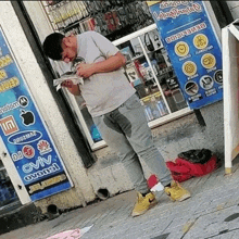 a man is standing on the sidewalk in front of a store while reading a newspaper .