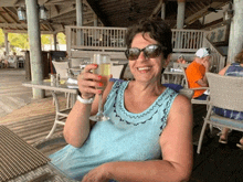 a woman is sitting at a table holding a glass of wine