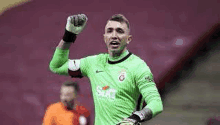 a soccer goalie is raising his fist in the air during a soccer game .