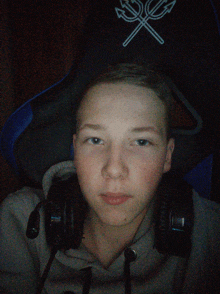 a young boy wearing headphones and a gaming chair with a crossed trident on it