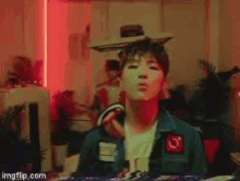 a man in a green jacket is dancing in a room with a red light behind him .