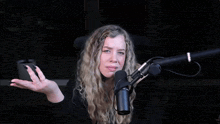 a woman is sitting in front of a rode brand microphone