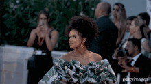 a woman in a green and white floral dress is standing in front of a crowd of people with the word getty images on the bottom