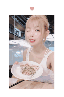 a woman is holding a plate of food with a pink heart in the corner