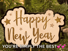 a wooden sign that says happy new year is hanging on a christmas tree .