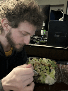 a man is eating a salad in front of a computer